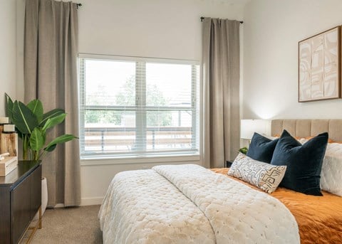 A bedroom with a large bed and a window with curtains.