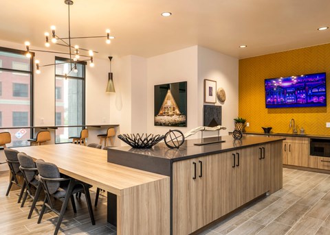 A modern kitchen with a long wooden island and a dining table with chairs.