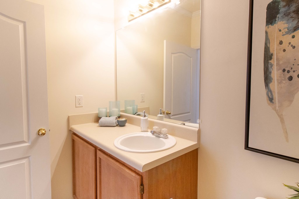 A bathroom with a sink, mirror, and a painting on the wall. at The Crest at Sugarloaf, Georgia