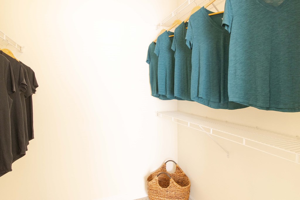 A row of teal shirts hanging on a white wall. at The Crest at Sugarloaf, Lawrenceville, GA