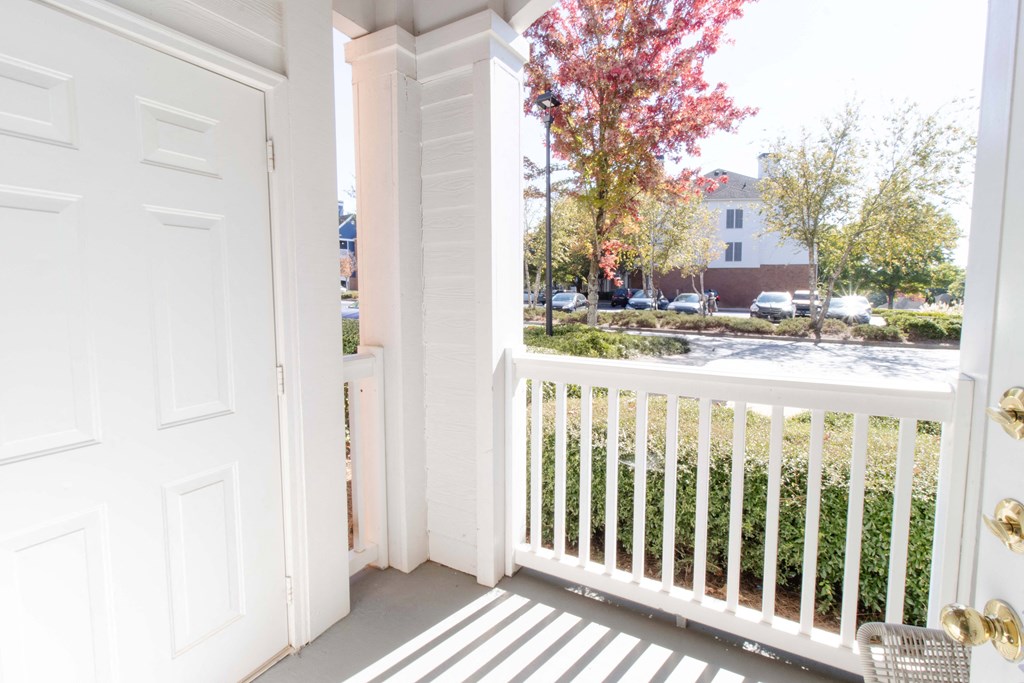 A white door is open to a balcony with a white railing. at The Crest at Sugarloaf, Lawrenceville, 30044