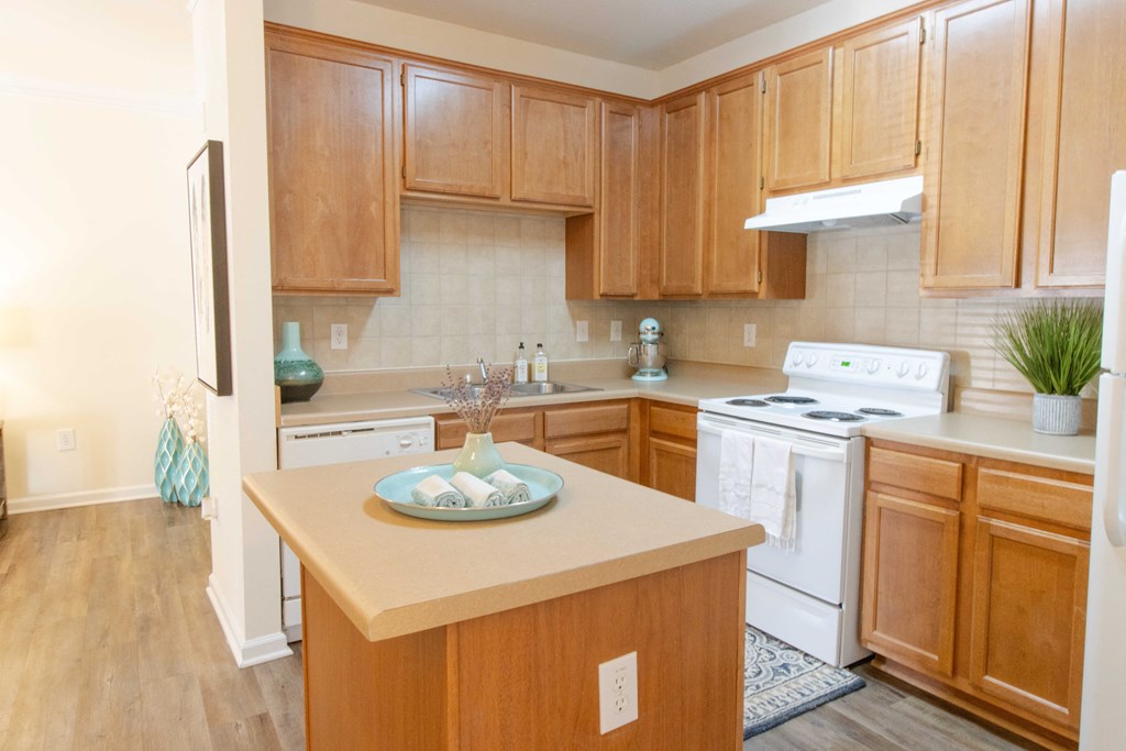 A kitchen with wooden cabinets and a white stove top oven. at The Crest at Sugarloaf, Lawrenceville, 30044