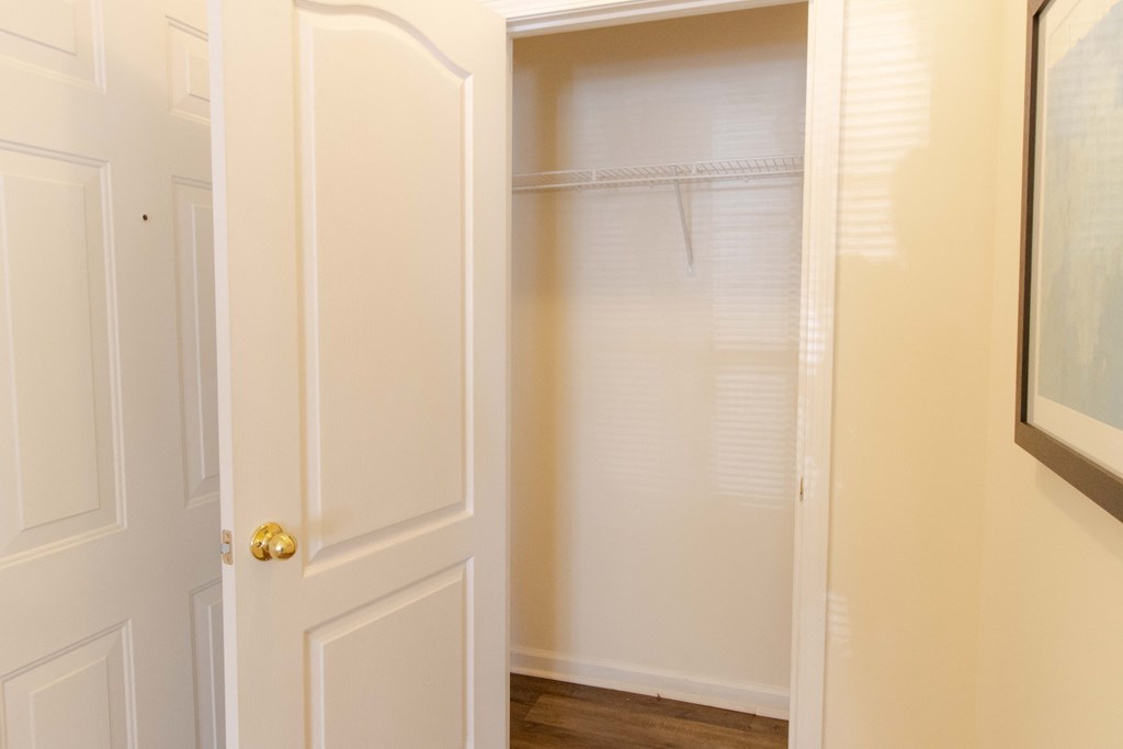 A white door with a gold handle is open to a white closet. at The Crest at Sugarloaf, Georgia, 30044