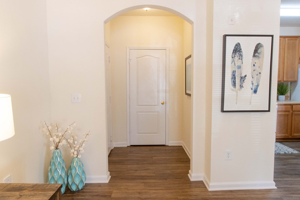 A hallway with a white door and a framed picture on the wall. at The Crest at Sugarloaf, Lawrenceville, 30044