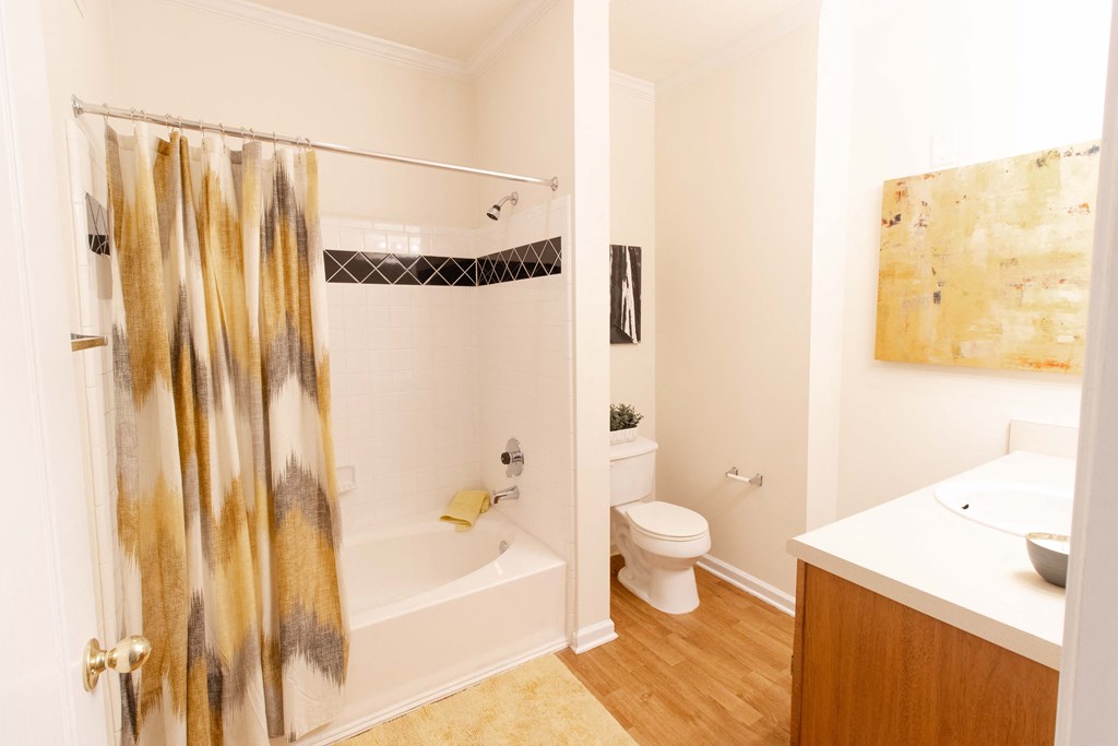 A bathroom with a shower curtain and a toilet. at The Crest at Sugarloaf, Lawrenceville, 30044