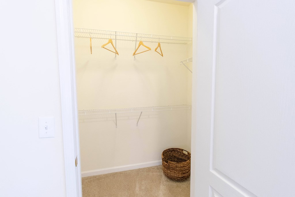 A white closet with a basket on the floor. at The Crest at Sugarloaf, Lawrenceville, 30044
