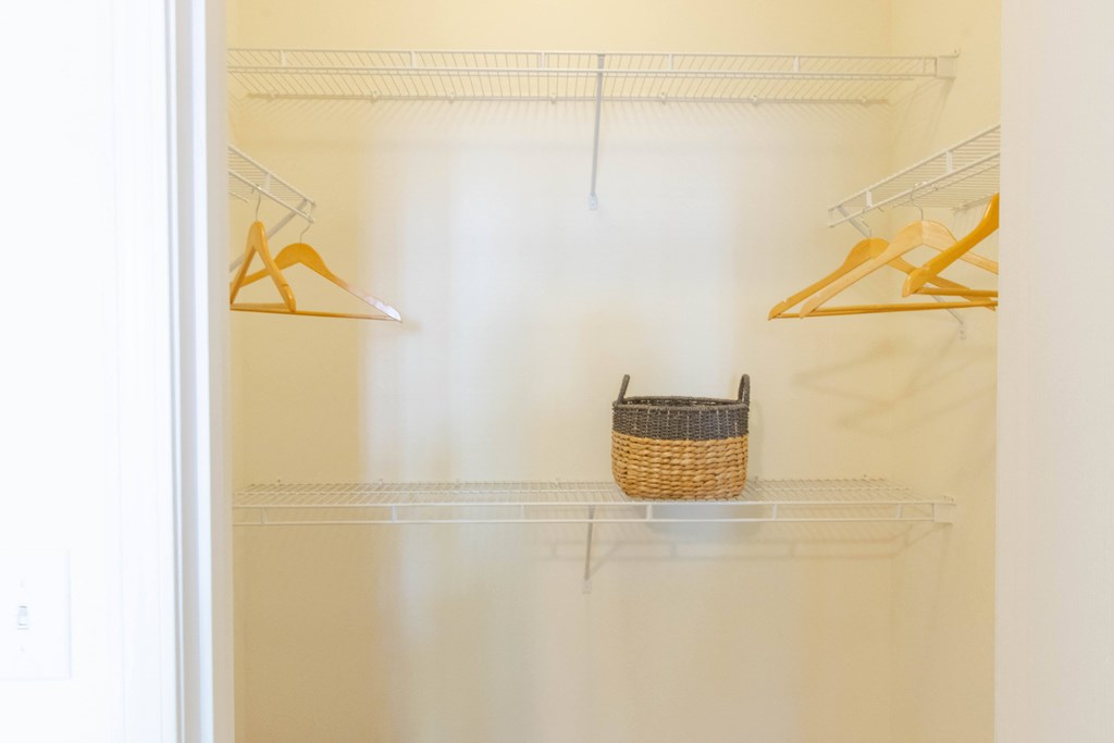 A white closet with a basket on the shelf. at The Crest at Sugarloaf, Lawrenceville, Georgia