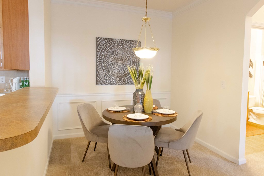 A dining room with a table set for two and a decorative piece hanging above it. at The Crest at Sugarloaf, Lawrenceville