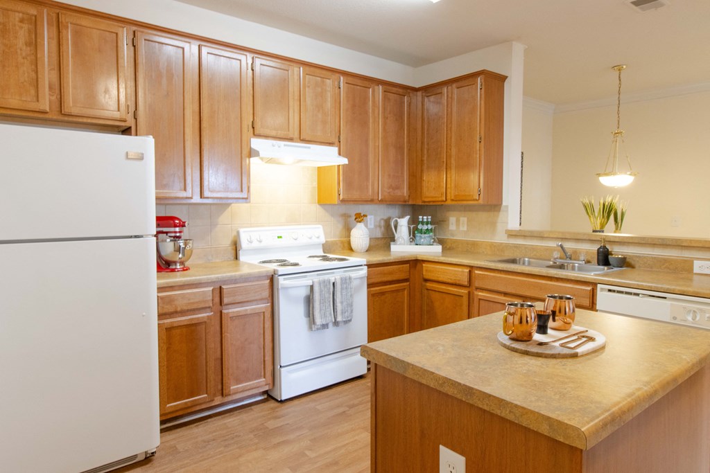 A kitchen with wooden cabinets and a white refrigerator at The Crest at Sugarloaf Apartments, Lawrenceville  30044
