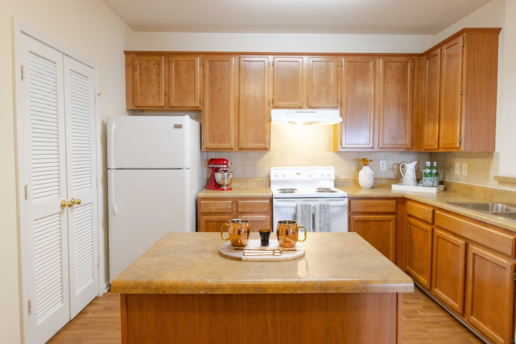 A kitchen with wooden cabinets and a white refrigerator. at The Crest at Sugarloaf Apartments, Lawrenceville , Georgia