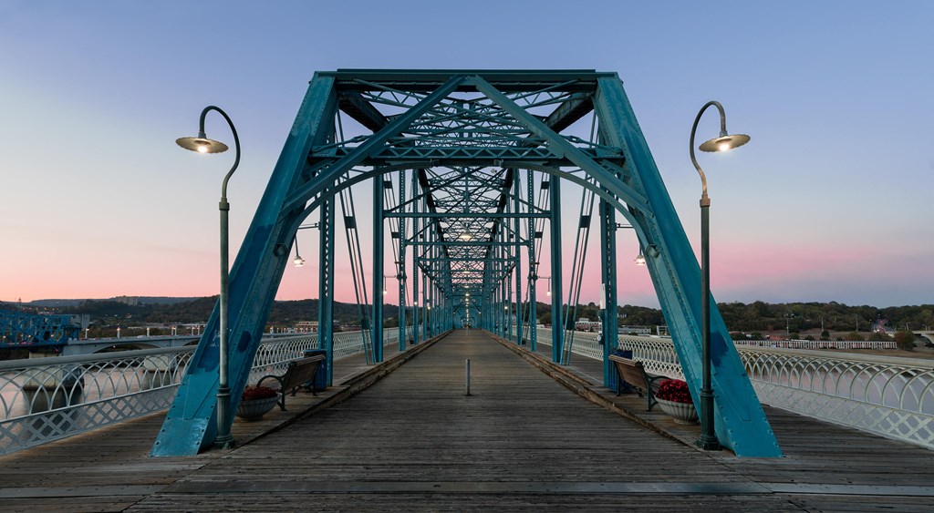 a bridge over the water at sunset with benches on it at District at Riverside Apartments, Tennessee, 37406