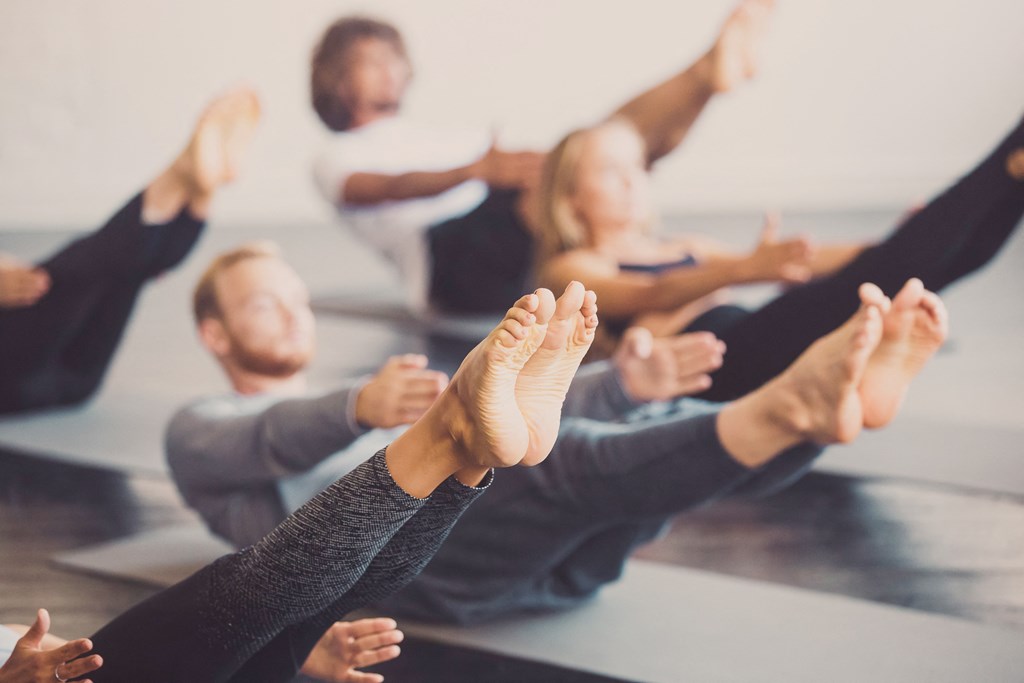 a group of people sitting in a yoga class with their hands up at District at Riverside Apartments, Tennessee