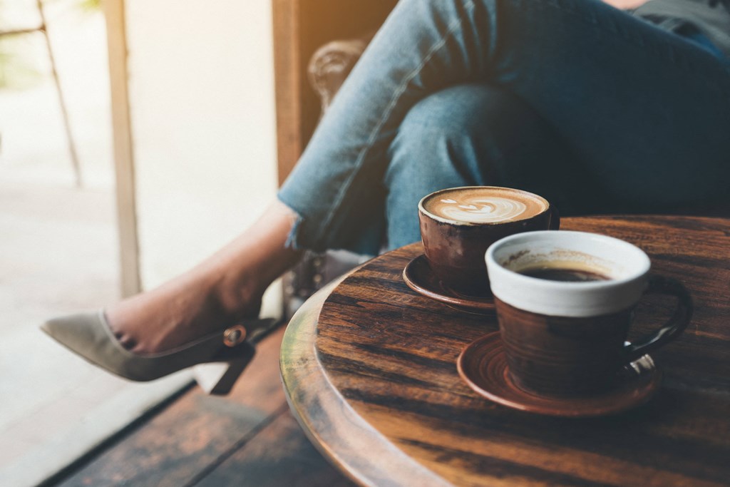 two cups of coffee sitting on a table next to a person at District at Riverside Apartments, Chattanooga, Tennessee