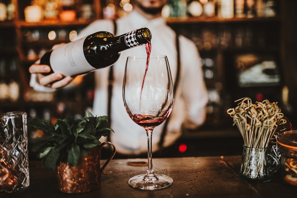 a man pouring wine into a glass in a bar at District at Riverside Apartments, Tennessee, 37406