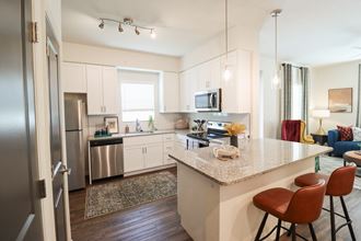The Crest at Naples Designer Kitchen with Stainless Steel Appliances a kitchen with stainless steel appliances and an island with stools