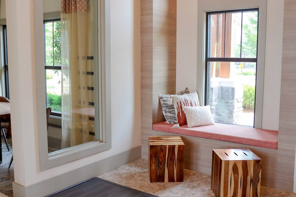 a window seat with a cushion and two wooden stools