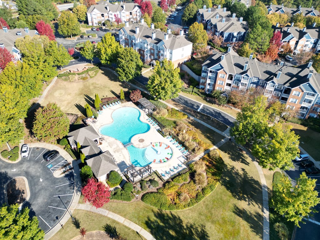 An aerial view of a residential area with a swimming pool and apartment buildings. at The Crest at Sugarloaf, Lawrenceville