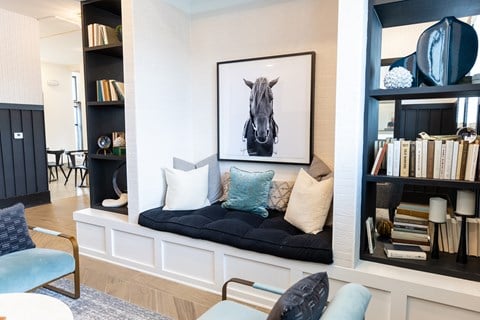 A living room with a black couch and a framed picture of a horse on the wall.