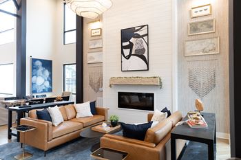 A living room with a fireplace and a painting above it at The Crest at South Point Apartments, Georgia