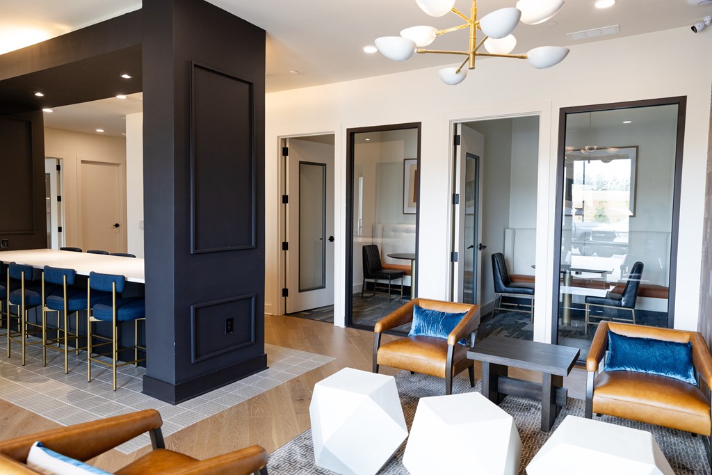 A modern living room with a dark wood fireplace and blue chairs at The Crest at South Point Apartments, Georgia