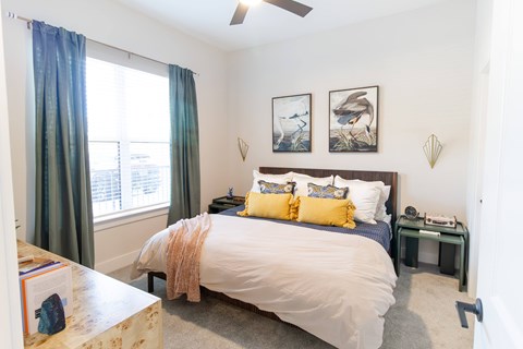 A bedroom with a bed, nightstand, and pictures on the wall.