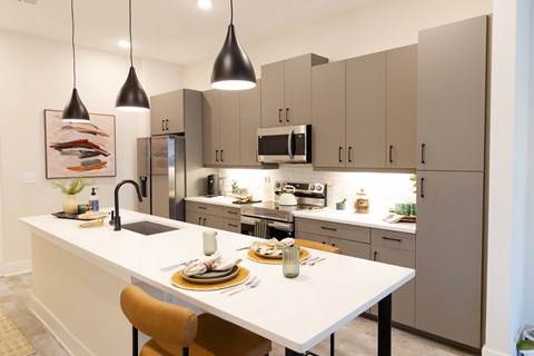A modern kitchen with a white island and grey cabinets.