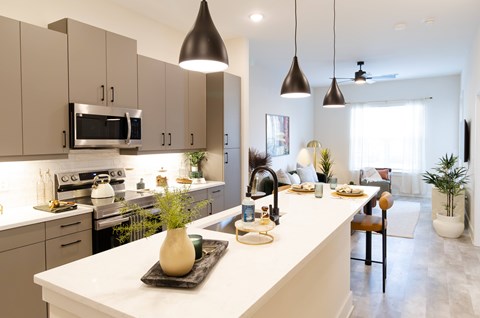 A modern kitchen with a white countertop and a black vase on it.