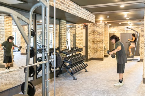 A man is working out in a gym with a barbell.
