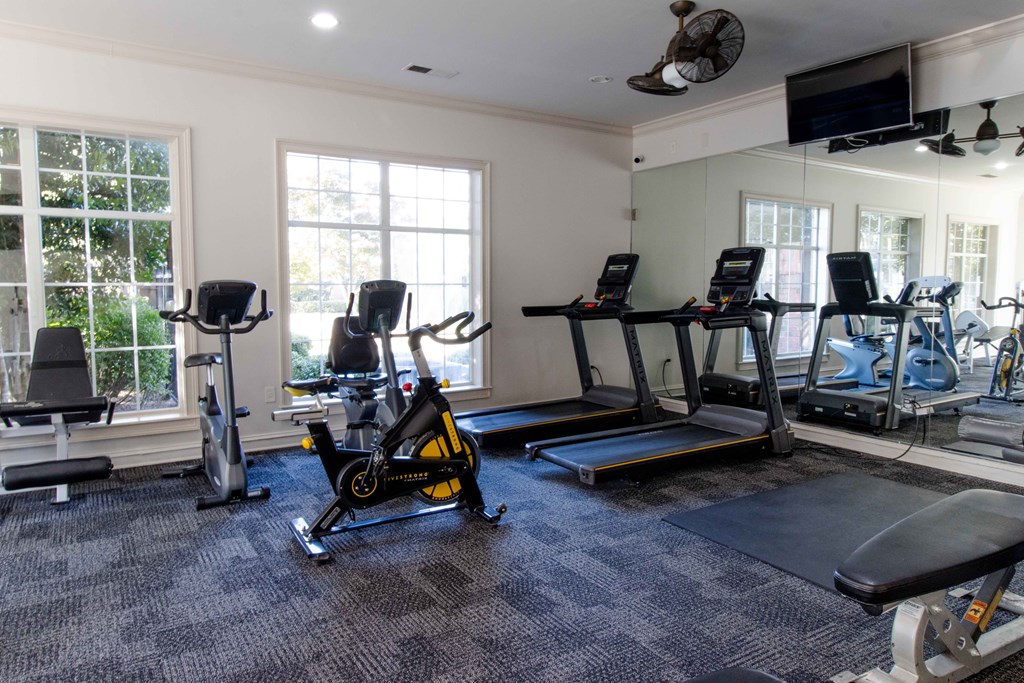A home gym with a variety of equipment including treadmills, stationary bikes, and weights. at The Crest at Sugarloaf, Lawrenceville