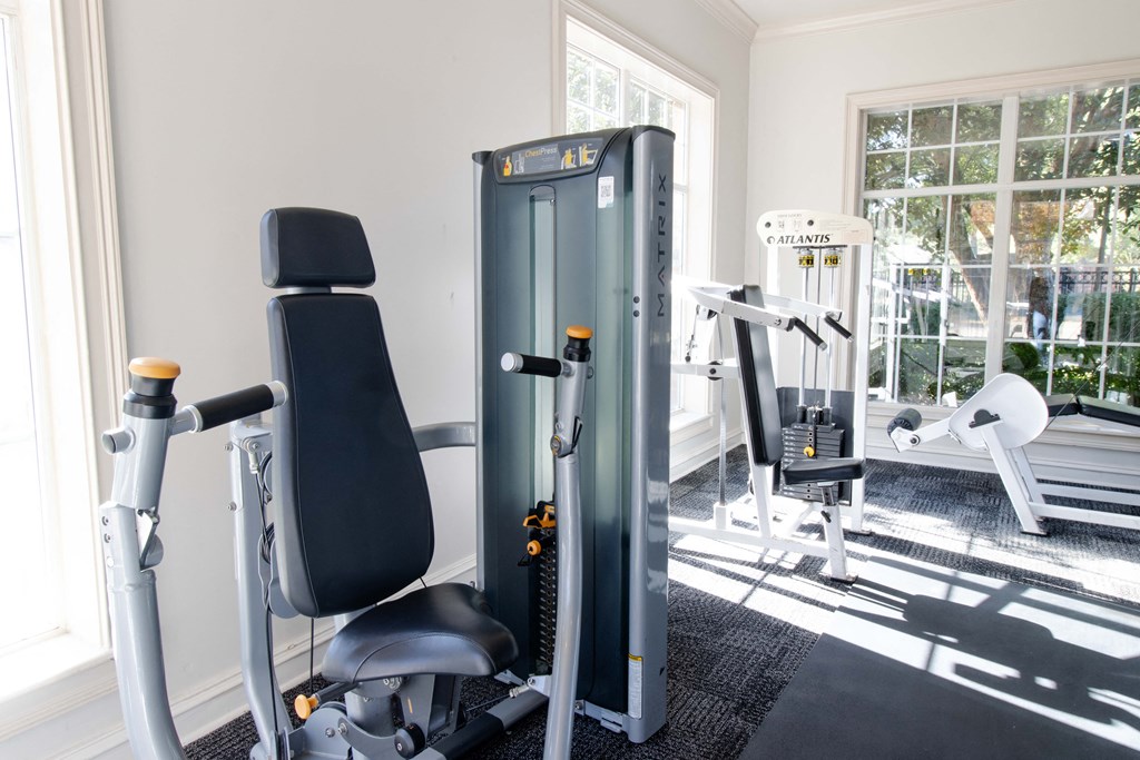 A gym with a black chair and a black and silver machine. at The Crest at Sugarloaf, Lawrenceville, Georgia