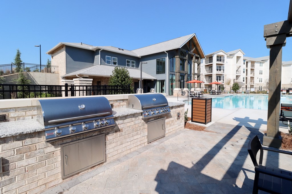 two bbq grills next to a pool with apartments in the background at The Crest at Acworth, Georgia