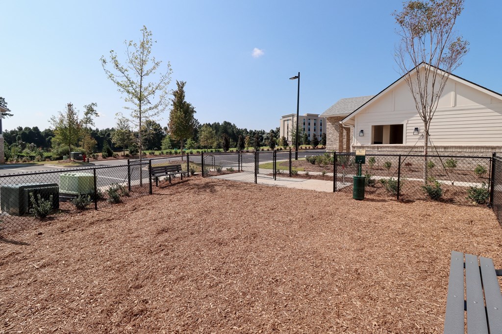 a fenced in dog park with a bench and a building in the background at The Crest at Acworth, Acworth, GA