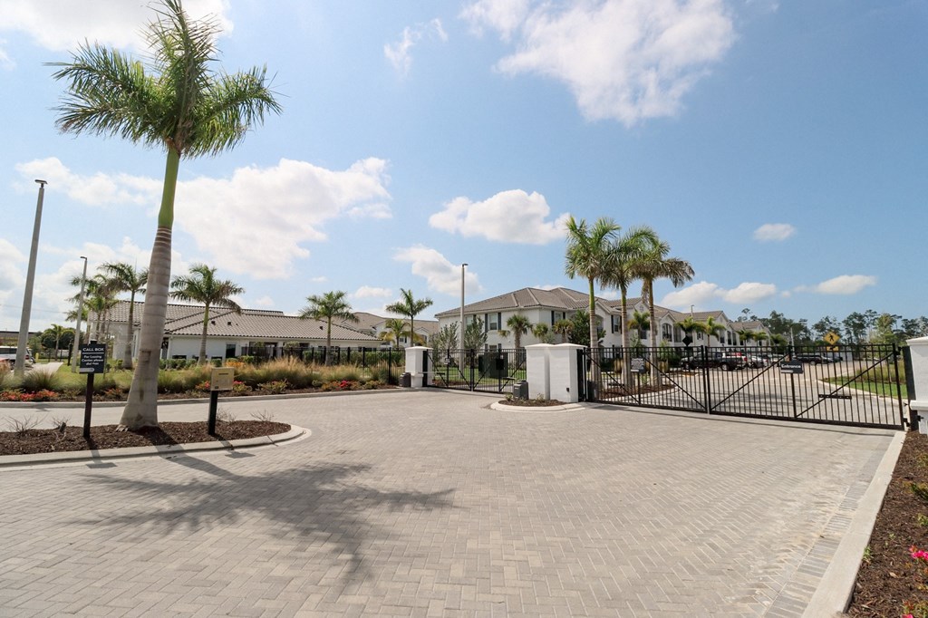 a driveway with palm trees and houses in the background at The Crest at Naples, Naples, Florida
