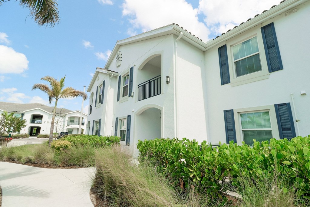a white building with a palm tree in the background at The Crest at Naples, Naples