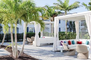 a patio with white furniture and palm trees