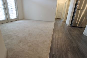 an empty living room with a hardwood floor and a stainless steel refrigerator at The Crest at Acworth, Acworth, 30102
