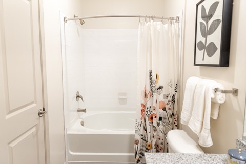 A white bathroom with a floral shower curtain.