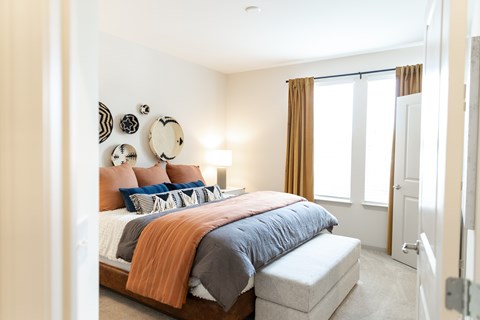 A bedroom with a bed, pillows, and a mirror on the wall.
