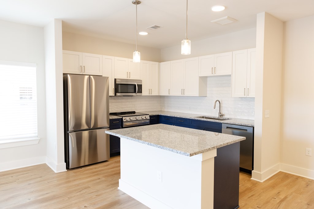A kitchen with a refrigerator, microwave, oven, and sink at The Crest at Oakwood Apartments, Georgia, 30566