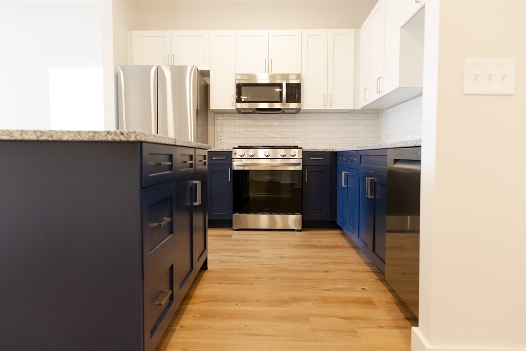 A kitchen with dark blue cabinets and a white countertop at The Crest at Oakwood Apartments, Oakwood , GA