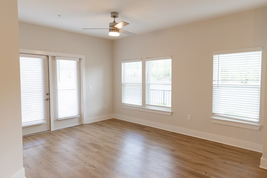 A room with a ceiling fan and three windows. at The Crest at Oakwood Apartments, Oakwood  30566