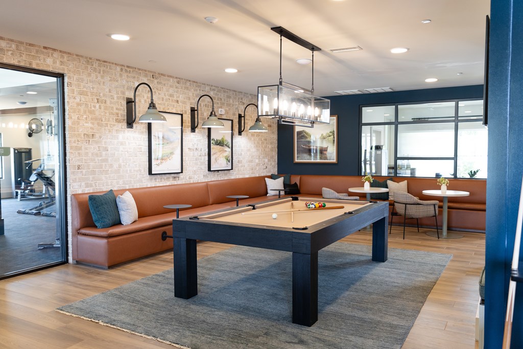 A billiard table is in the middle of a room with a brick wall and a mirror. at The Crest at Oakwood Apartments, Oakwood , GA, 30566