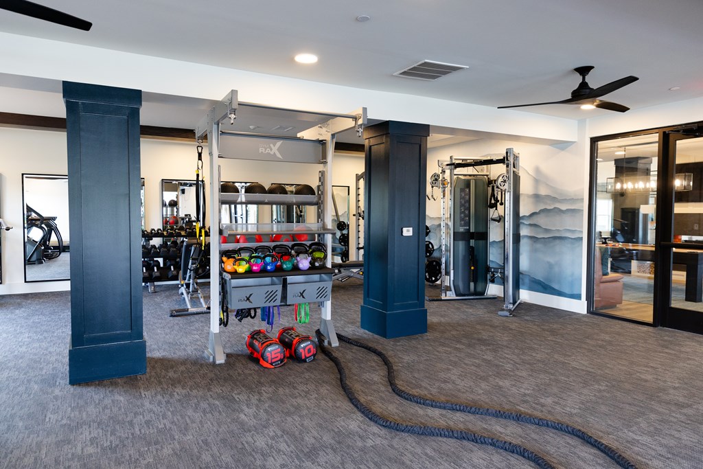A gym with a variety of equipment including a treadmill, weights, and a rowing machine. at The Crest at Oakwood Apartments, Oakwood , Georgia