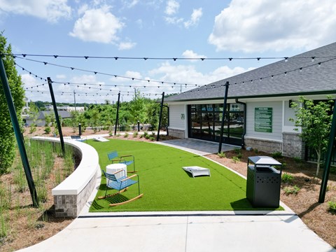 A playground area with a slide and a green lawn. at The Crest at Oakwood Apartments, Georgia, 30566
