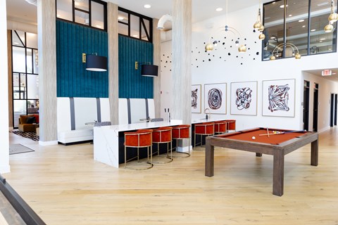 A room with a pool table and a shelf with artwork.