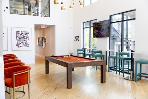 A room with a pool table and chairs.