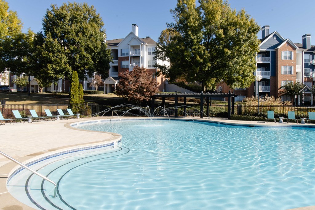 A large swimming pool surrounded by trees and chairs. at The Crest at Sugarloaf Apartments, Lawrenceville , GA