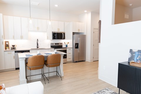 White kitchen with island seating and pendant lights at District on the Etowah Apartments, Canton