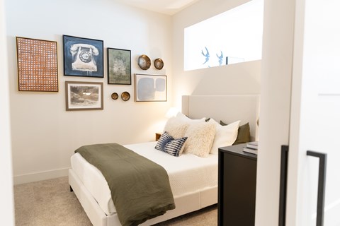 Guest bedroom with gallery wall and upholstered headboard at District on the Etowah Apartments, Georgia