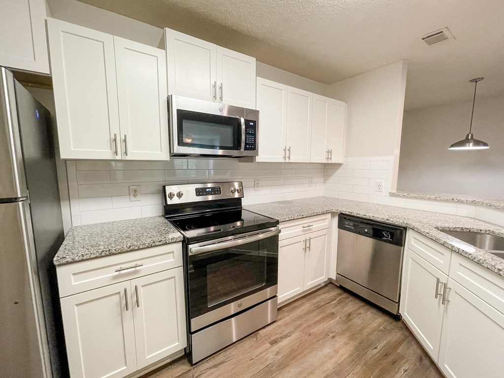 The Crest at Berkeley Lake St James renovated kitchen with granite countertops and stainless steel appliances located in Duluth, GA 30096